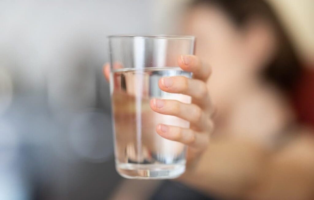 a woman holding a glass of water - qnet water purifier