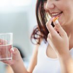 Shot of a young woman taking supplements with a glass of water during her morning routine at home for an enhanced lifestyle