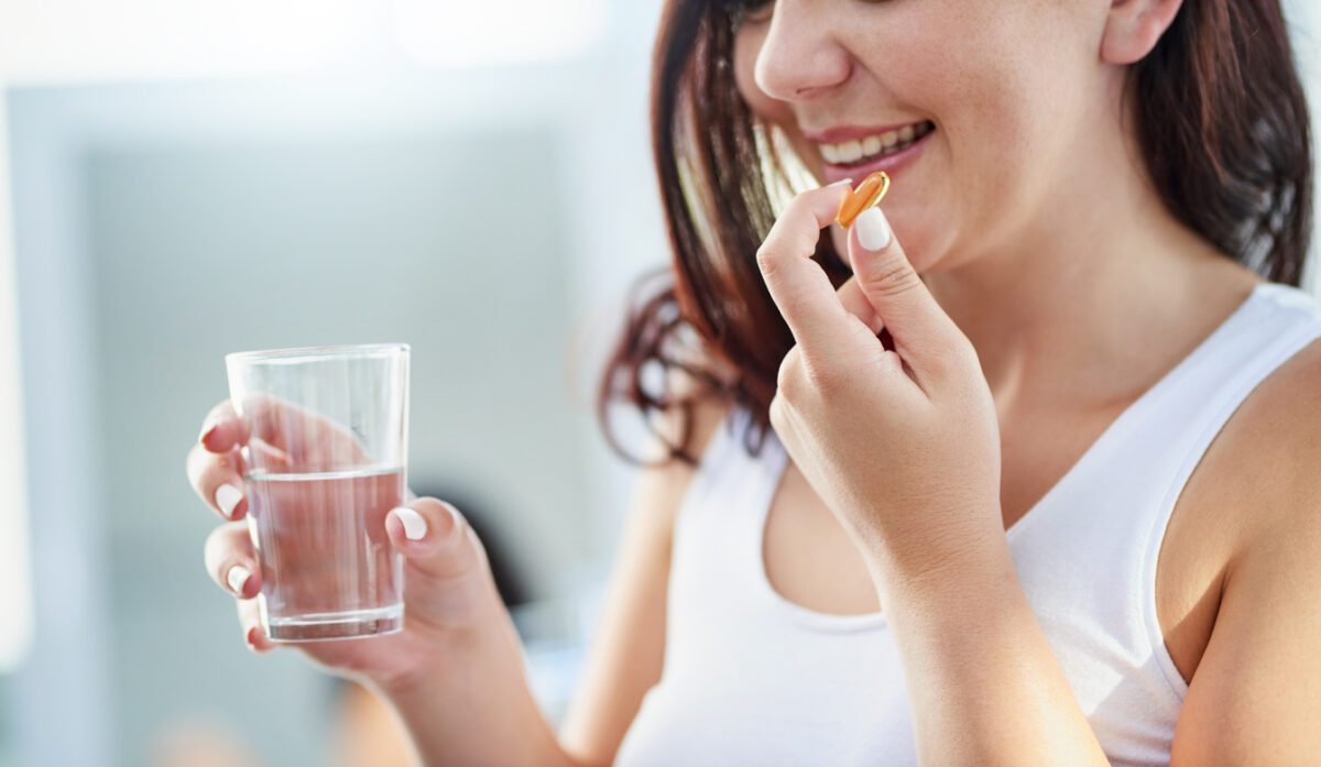 Shot of a young woman taking supplements with a glass of water during her morning routine at home for an enhanced lifestyle