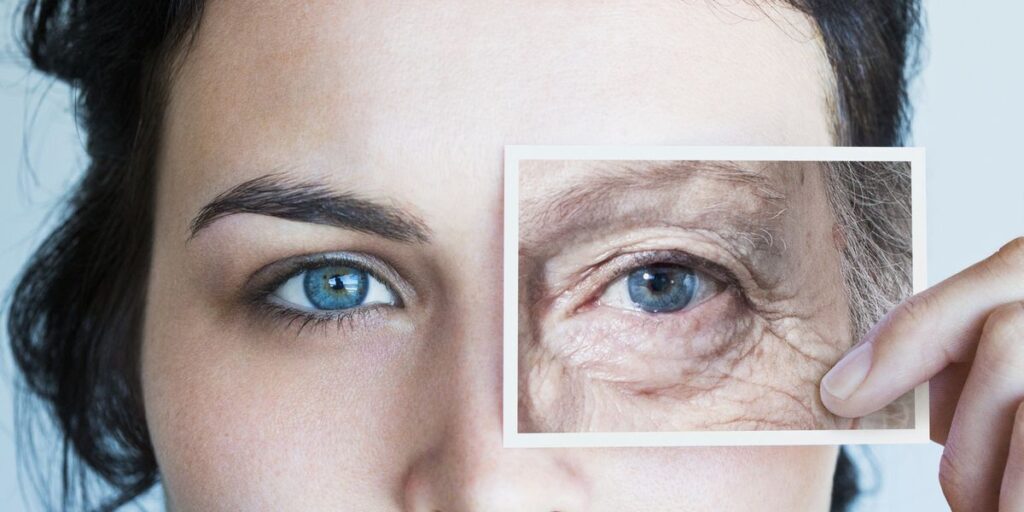 a woman holding a card with older wrinkled skin next to her younger looking skin - pm skincare routine 
